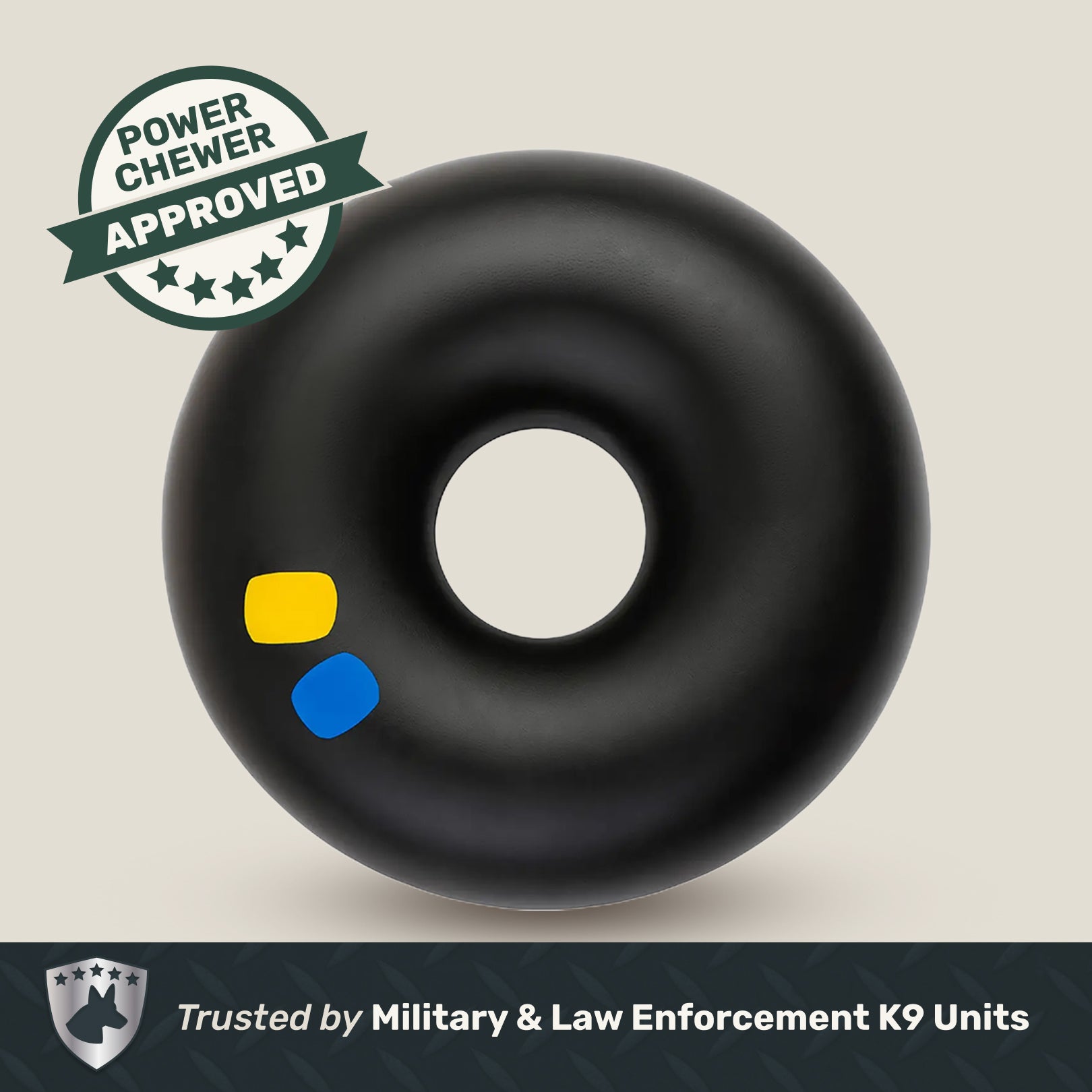Black donut-shaped rubber toy product with saftey indicators and 'Power Chewer Approved' label on a beige background.