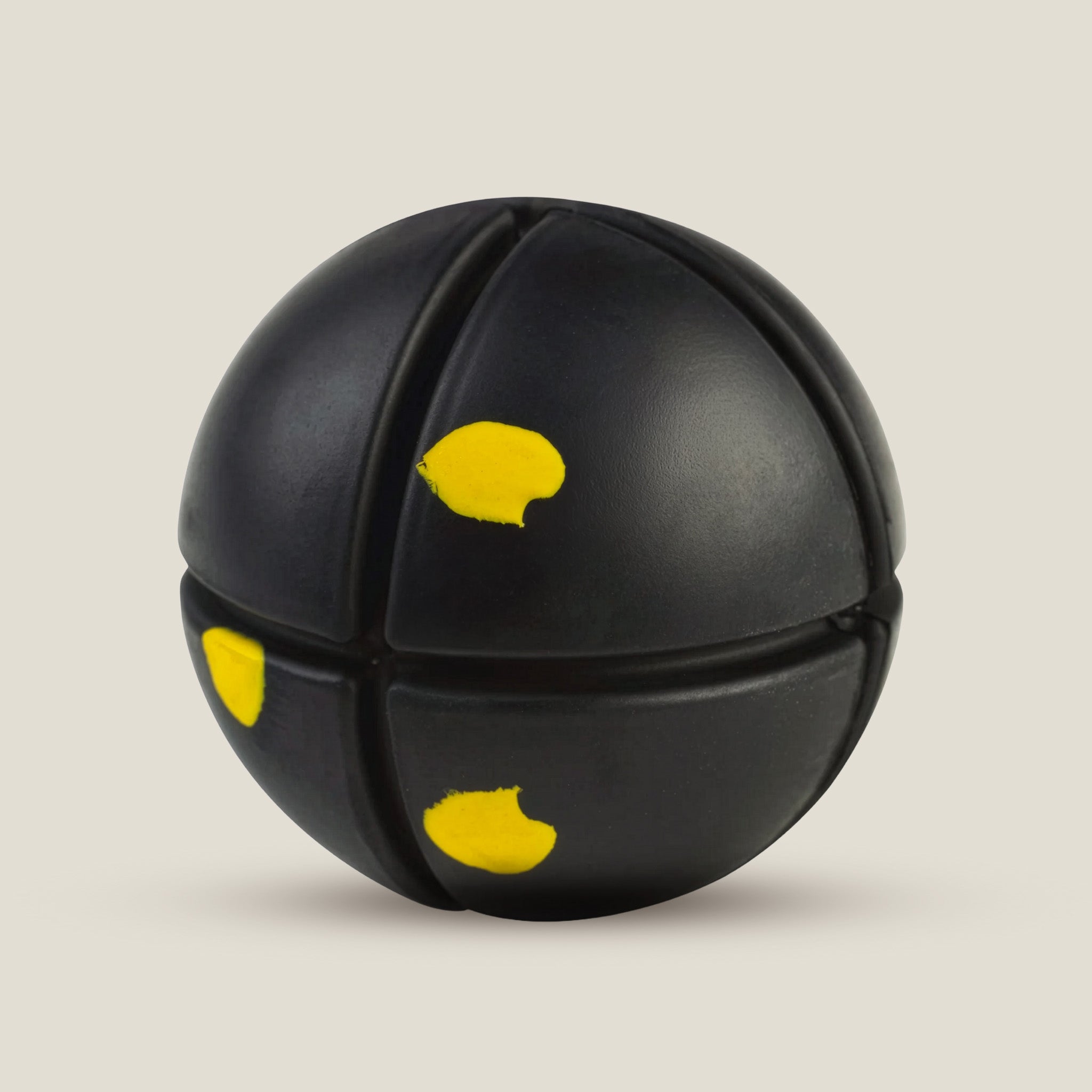 Black rubber ball with yellow saftey indicators on a beige background